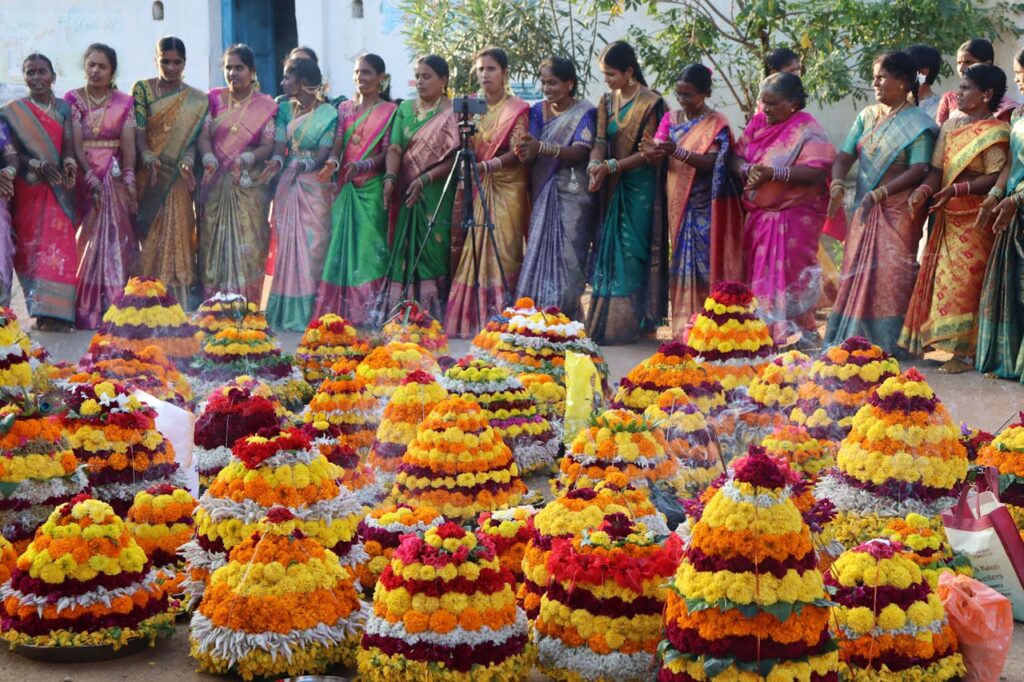 Vibrant display of women celebrating the Bathukamma festival with colorful flower arrangements in India.